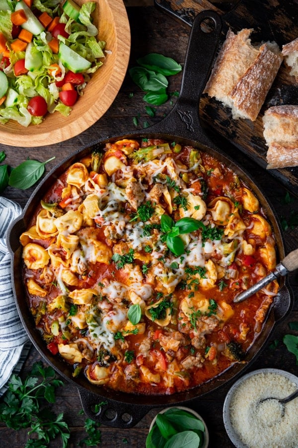 Overhead image of a cast iron skillet with the best cheese tortellini recipe and Italian sausage