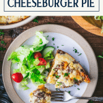 Slice of impossible cheeseburger pie on a plate with text title box at top