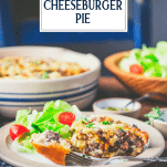 Side shot of impossible cheeseburger pie on a plate with a side salad and text title overlay