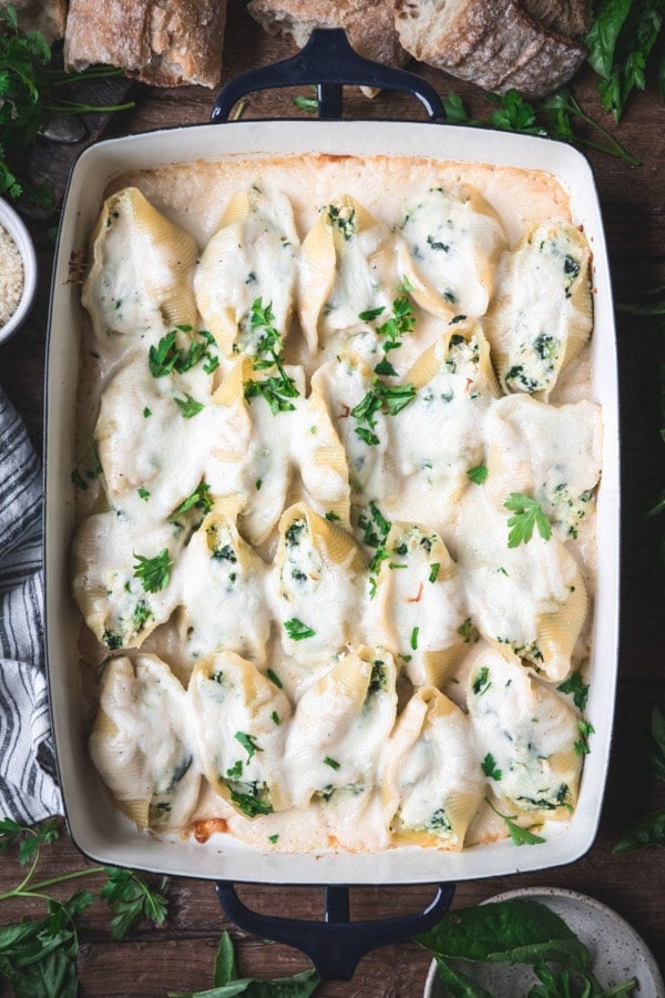 Overhead shot of creamy chicken stuffed shells in a blue baking dish on a table