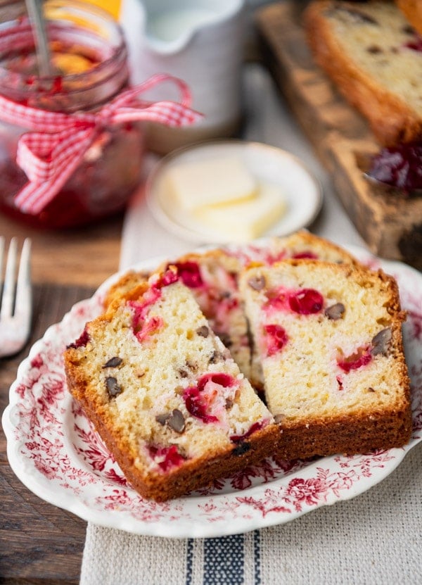 Slices of homemade cranberry bread with walnuts served on a pink and white patterned plate.