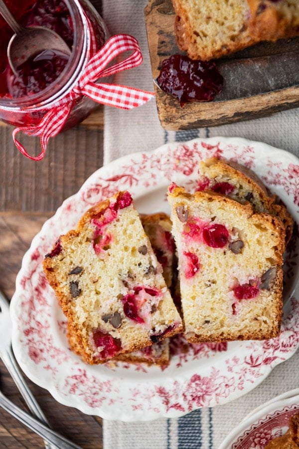 Stacked slices of cranberry bread, cut in half, and served on a pink and white patterned platter.