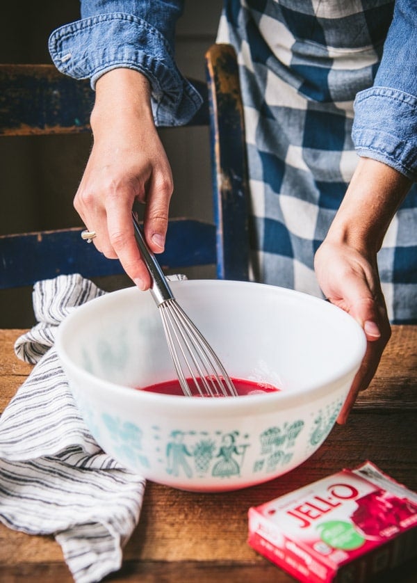 Whisking together jello in a white mixing bowl.