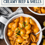 Overhead shot of a bowl of creamy beef and shells with text title box at top