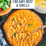 Overhead shot of creamy beef and shells in a skillet with text title overlay