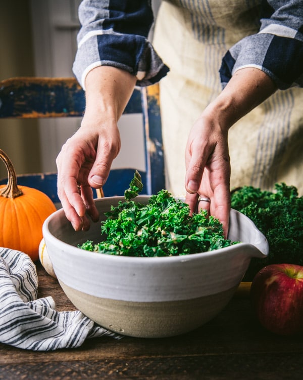 Massaging kale with dressing in a bowl