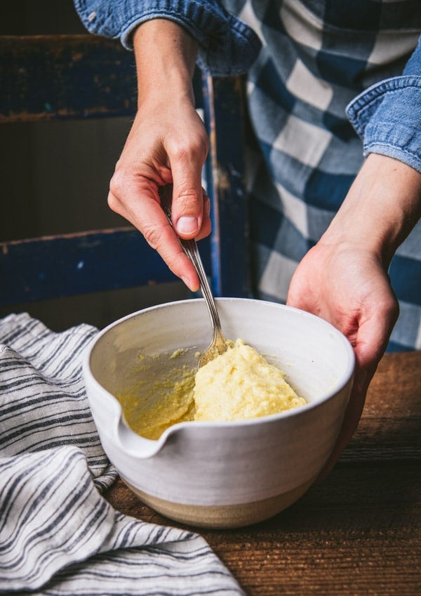 Stirring together cornbread batter in a white bowl