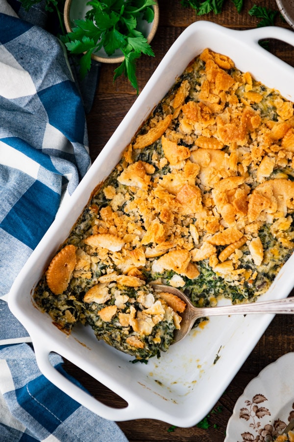 Close overhead image of a pan of creamed spinach casserole on a wooden table.