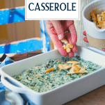 Sprinkling topping over creamed spinach casserole with text title overlay