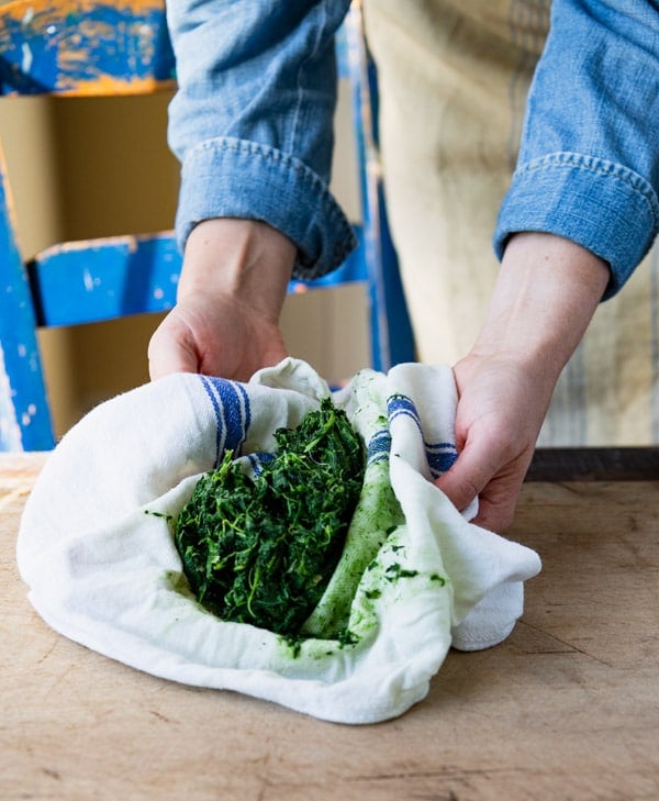 Squeezing spinach dry in a dish towel