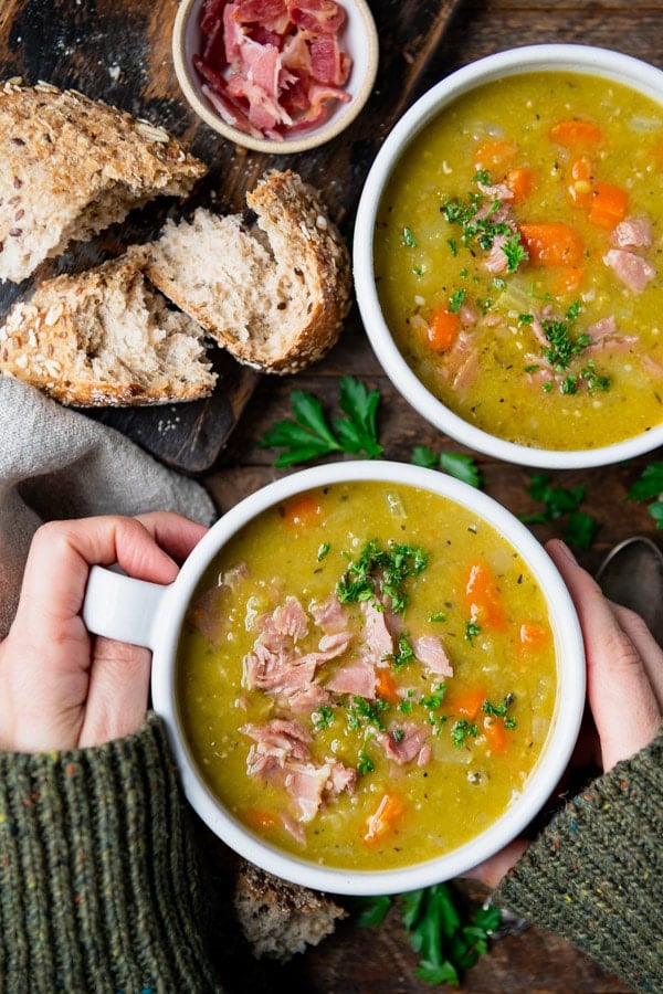 Hands holding a bowl of crockpot split pea soup.