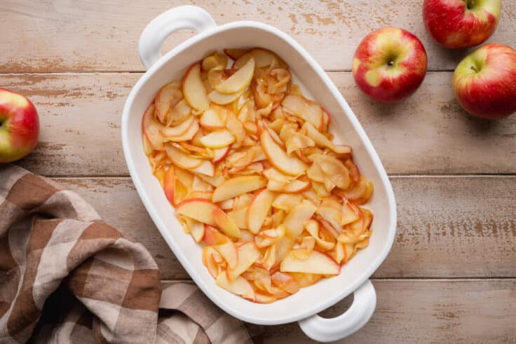 Sauteed apples spread in a white baking dish.