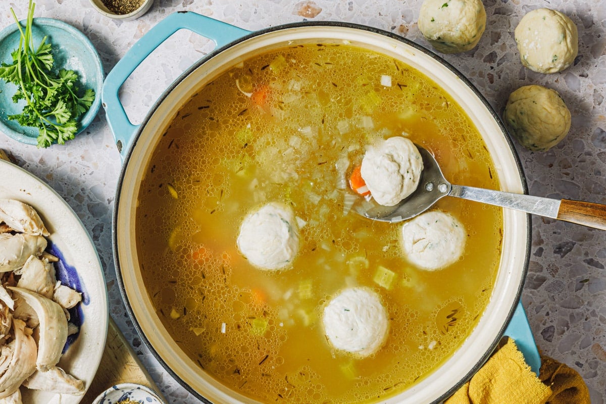 Adding the dumplings to a pot of chicken soup.