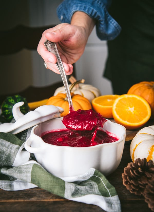 Ladling the best cranberry sauce recipe from a white bowl