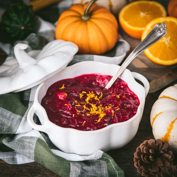Square image of easy cranberry sauce on a table with oranges