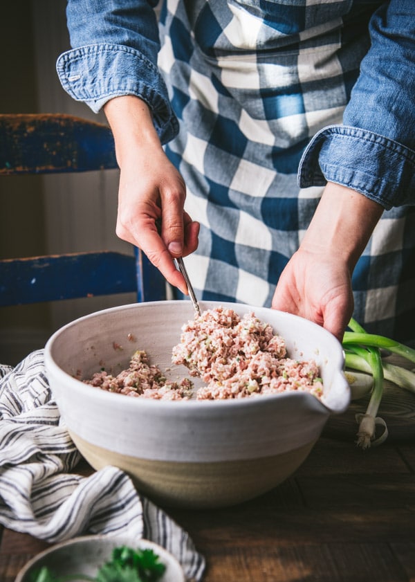 Stirring together ham salad in a white mixing bowl