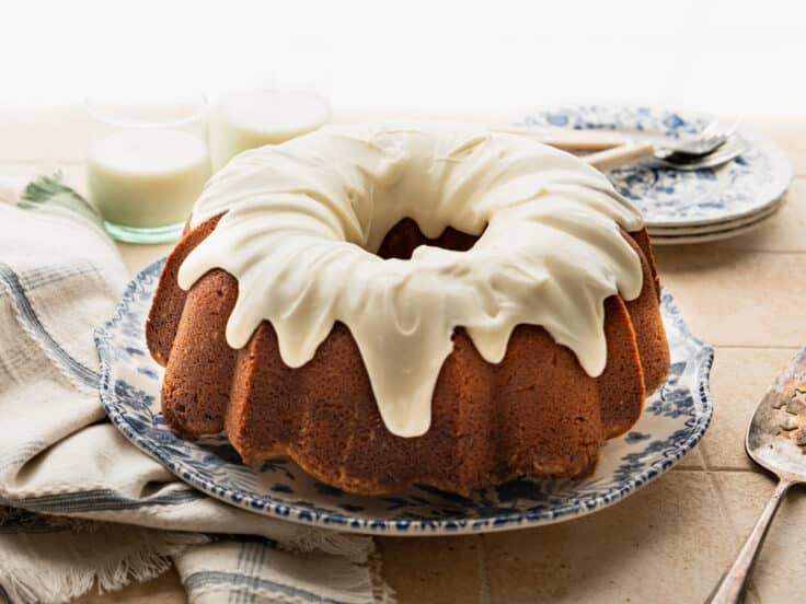 Horizontal side shot of vanilla icing on a vanilla pound cake recipe before slicing.