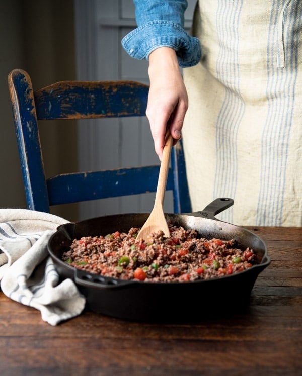 Stirring ground beef and vegetables in a skillet