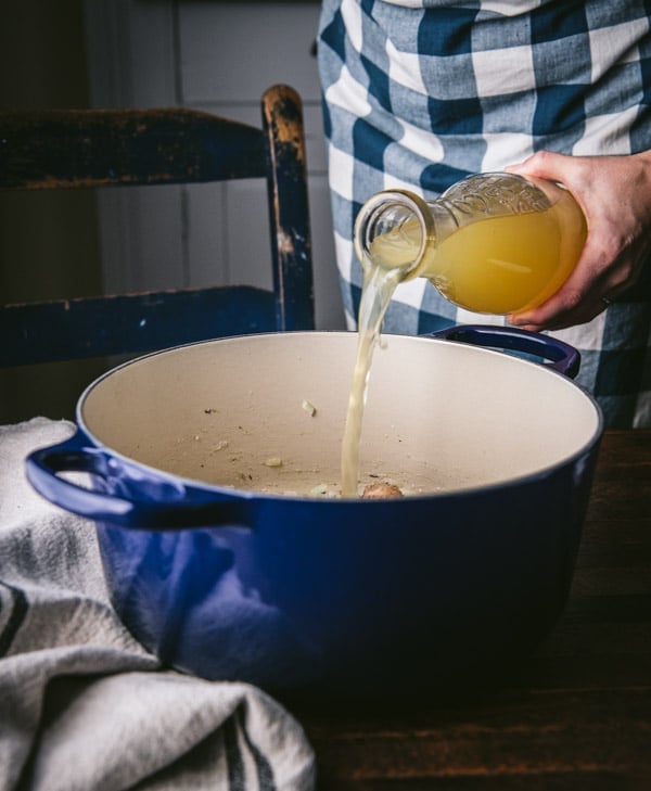 Pouring chicken broth into a pot.