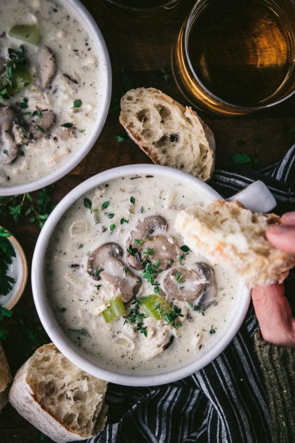 Dipping bread in a bowl of creamy chicken and wild rice soup