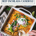 Spoon in a dish of beef enchilada casserole with text title box at top.