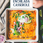 Hands holding a pan of beef enchilada casserole with text title overlay.