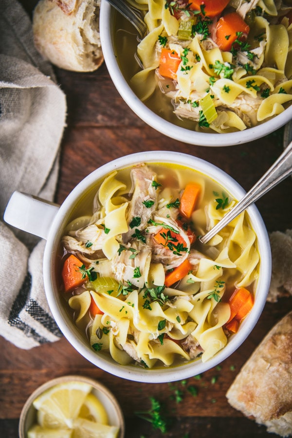 Close overhead shot of a bowl of homemade chicken noodle soup on a wooden table.