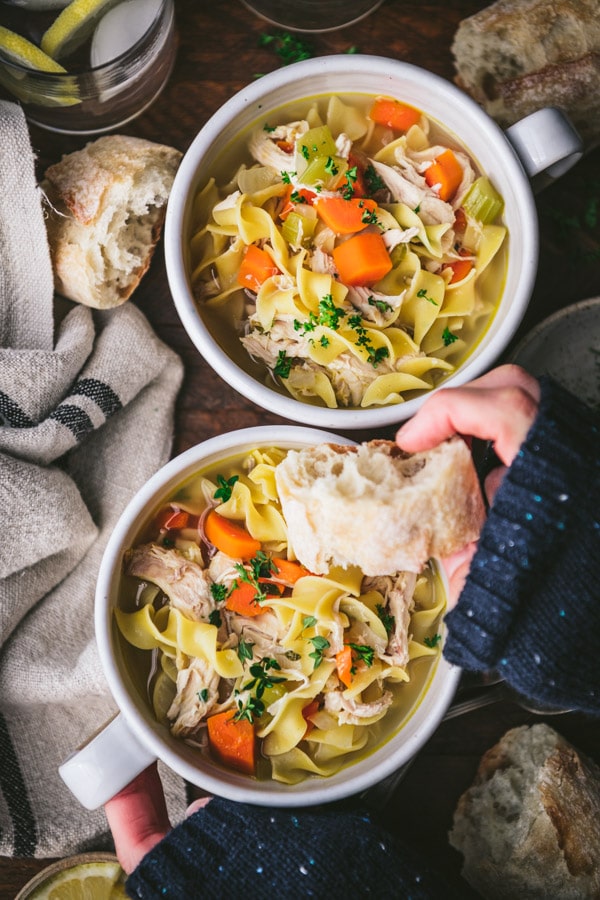 Dipping bread in a bowl of the best chicken noodle soup recipe.