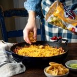 Sprinkling fritos on top of a casserole.