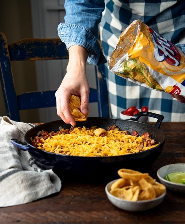 Sprinkling fritos on top of a casserole.
