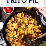 Hands holding a pan of frito pie with text title box at top.