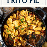 Serving spoon in a dish of frito pie with text title box at top.