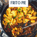 Close overhead image of a pan of frito pie chili cheese casserole with text title overlay