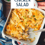 Hands holding a dish of hot chicken salad casserole with text title overlay.