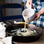 Pouring clam juice and white wine in a cast iron skillet.