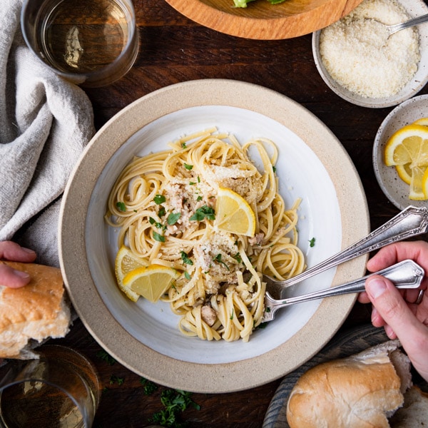 Overhead shot of a dinner table with linguine with clam sauce, salad, bread and wine.