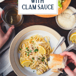 Overhead shot of a dinner table with a bowl of linguine with white clam sauce and bread and salad and text title overlay at top.