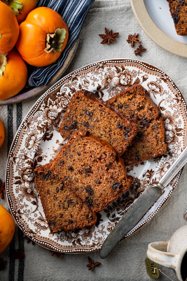 Overhead shot of the best persimmon bread recipe, sliced into thick pieces and served on a brown and white platter.
