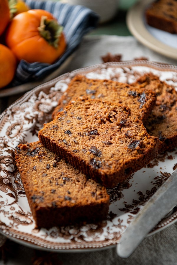 A platter filled with thick slices of moist persimmon bread.