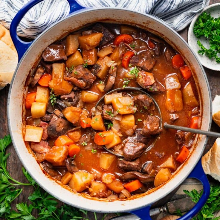 Ladle in a Dutch oven full of beef burgundy.