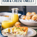 Side shot of a square of baked ham and cheese omelet on a plate with text title box at top.