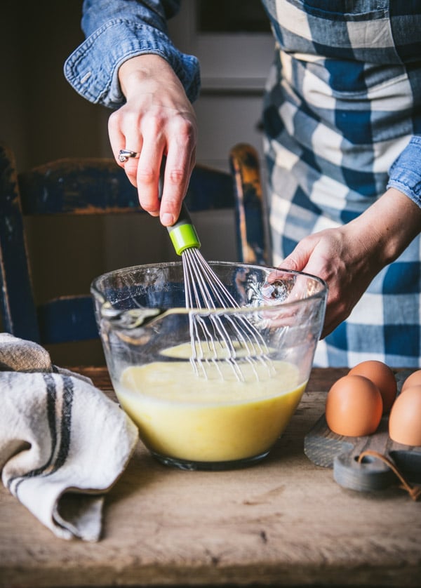 Whisking eggs with milk in a glass bowl.
