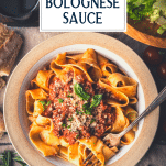 Overhead shot of a bowl of bolognese sauce with pasta and text title overlay