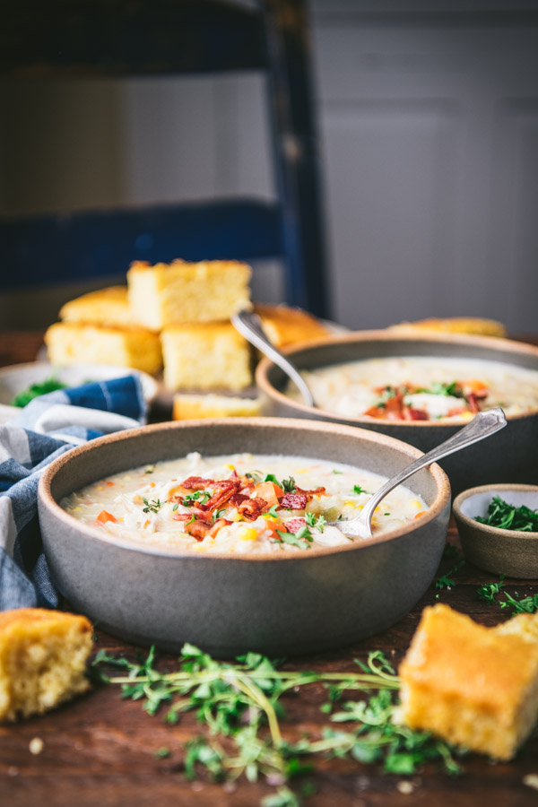 Side shot of a dinner table with a tray of cornbread and two bowls of chicken corn chowder