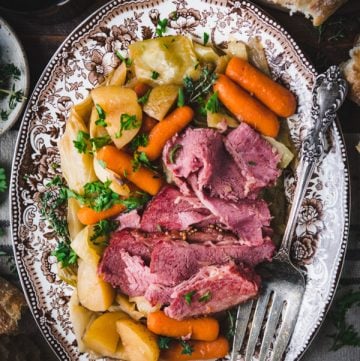 Serving tray with crockpot corned beef and cabbage with carrots and potatoes.
