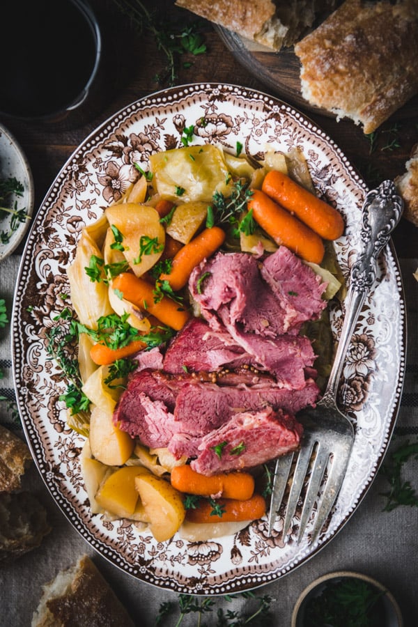 Serving tray with crockpot corned beef and cabbage with carrots and potatoes.