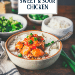 Chinese sweet and sour chicken in a bowl with rice on a table and text title overlay