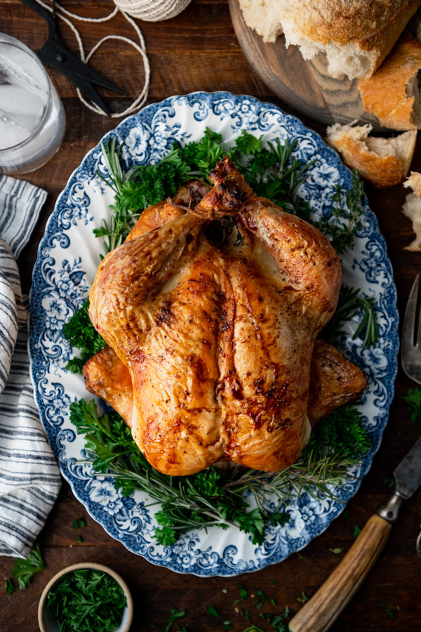 Overhead image of crisp and juicy whole roasted chicken on a dinner table.