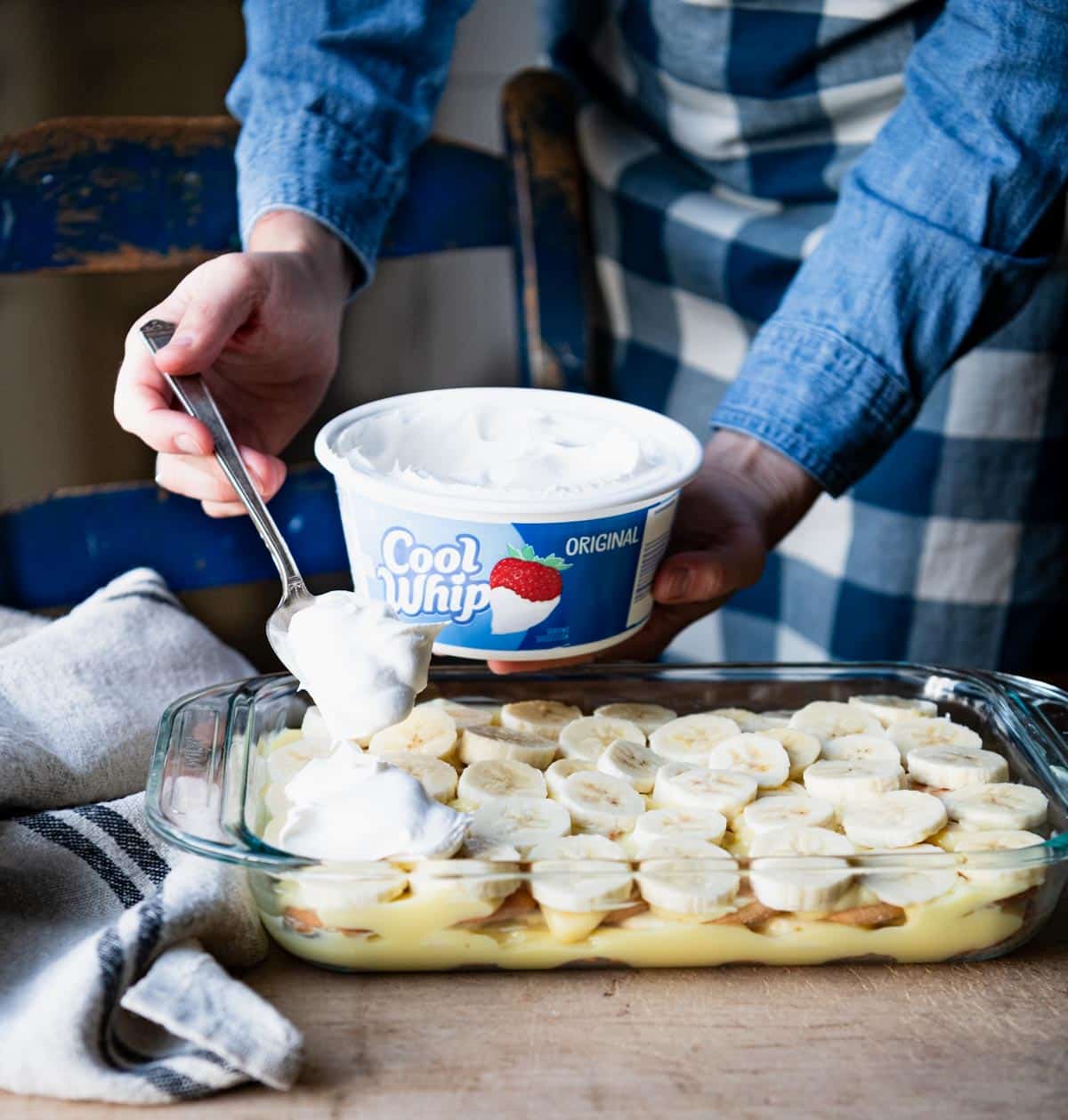 Spreading cool whip on top of banana pudding.