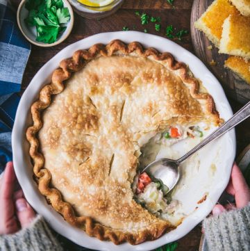 Hands holding the best chicken pot pie recipe on a wooden table.